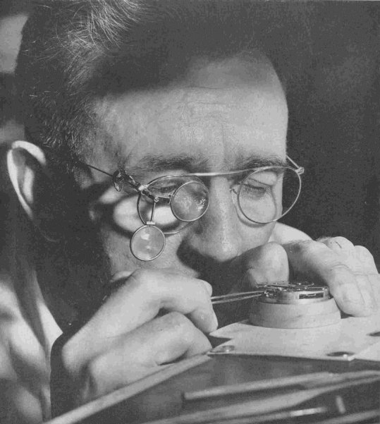 Vintage watchmaker examining a watch with a magnifying glass 