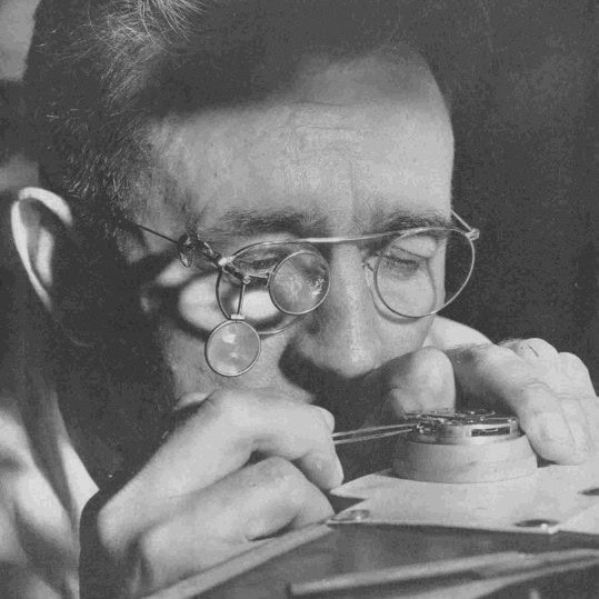 Historical aviator examining a watch with magnifying glass, aviation heritage of AVIGO Watch Company 